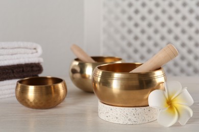 Photo of Composition with golden singing bowls on white wooden table