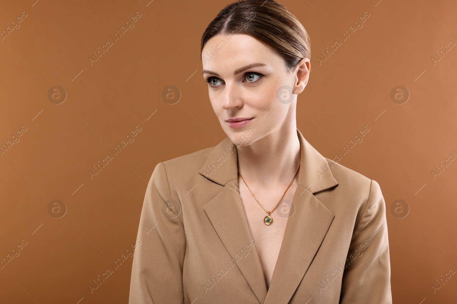 Photo of Beautiful woman with elegant necklace on brown background