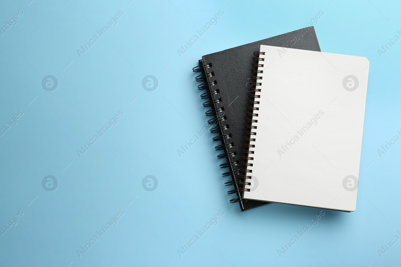 Photo of Notebooks on black background, top view. Space for text