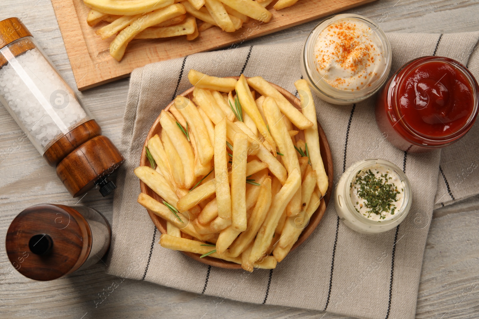 Photo of Delicious french fries served with sauces on light wooden table, flat lay