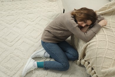 Photo of Sad young woman sitting on floor at home