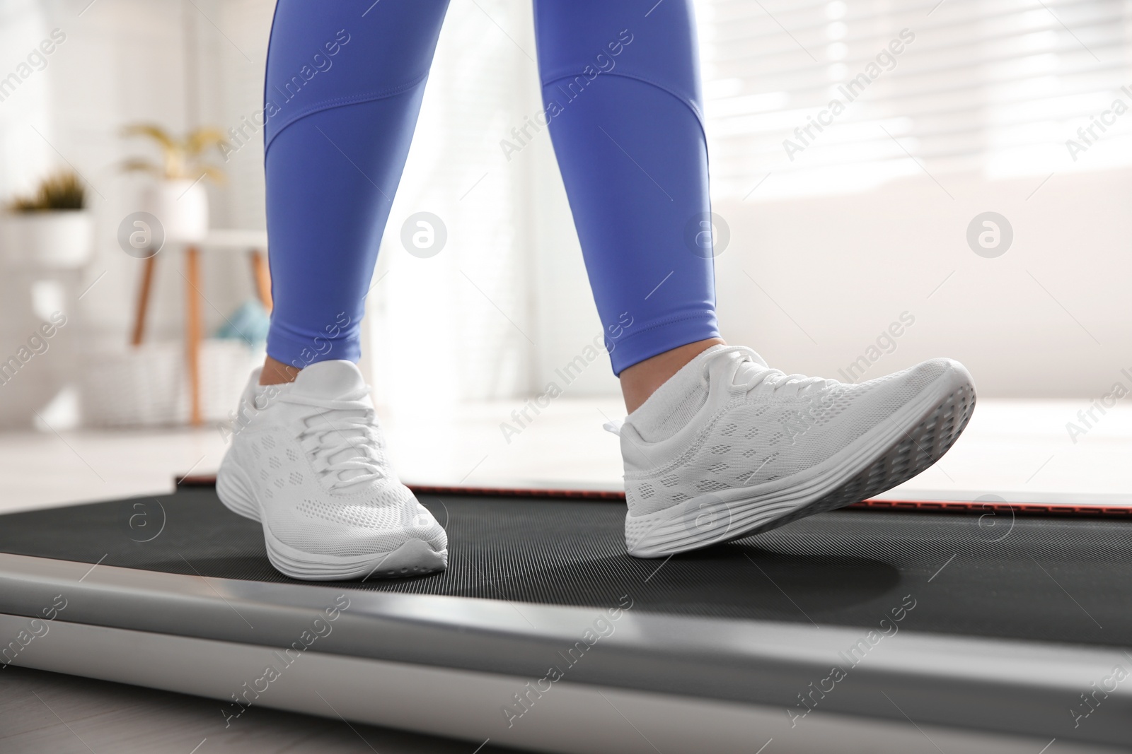 Photo of Sporty woman training on walking treadmill at home, closeup