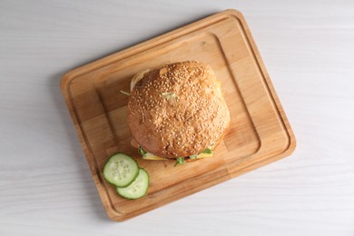 Photo of Board with delicious vegetarian burger on white wooden table, top view