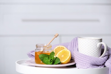 Cup with hot tea, lemon and honey on table