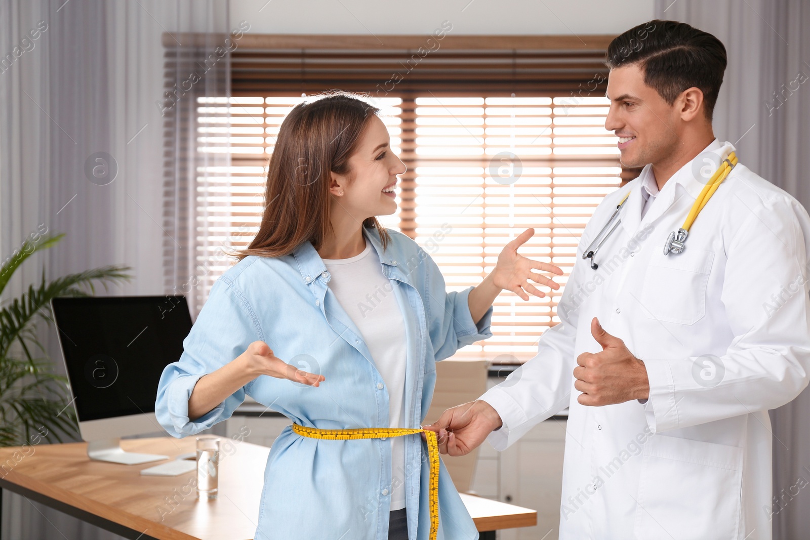 Photo of Nutritionist measuring young patient's waist in clinic