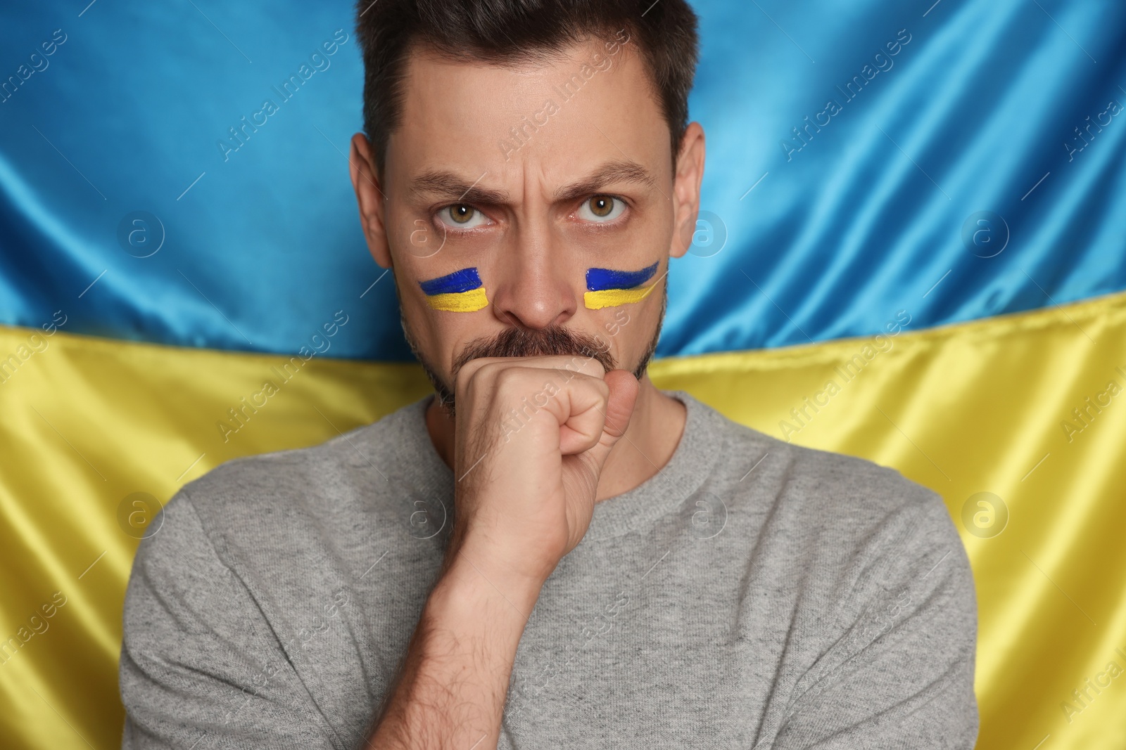 Photo of Angry man with face paint near Ukrainian flag