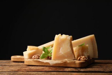 Photo of Delicious parmesan cheese with walnuts and basil on wooden table. Space for text