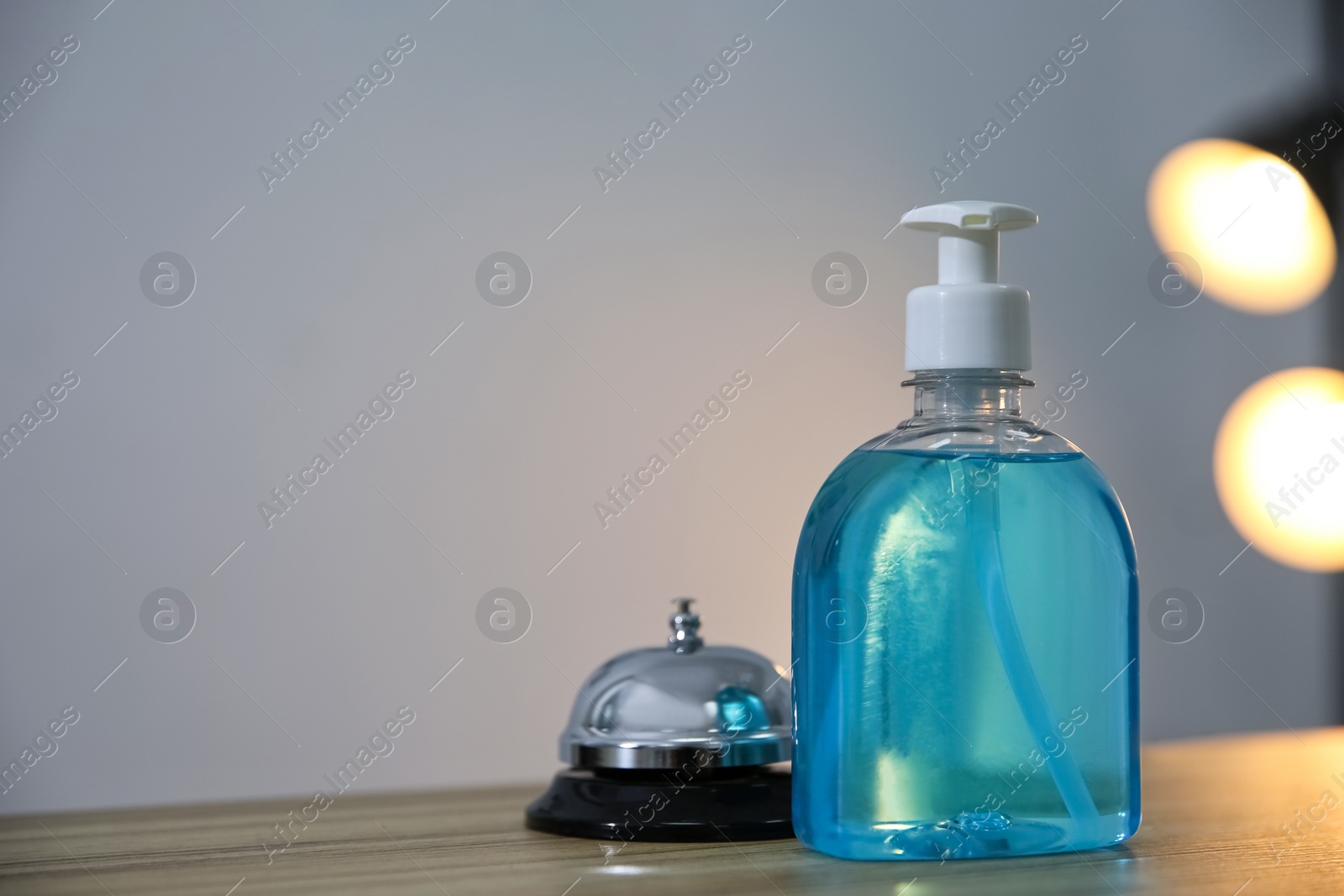 Photo of Dispenser bottleantiseptic gel and service bell on reception desk in hotel. Space for text
