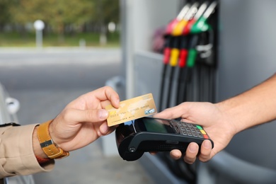 Photo of Man sitting in car and paying with credit card at gas station, closeup
