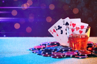 Image of Alcohol drink, playing cards and casino chips on table against blurred lights, space for text. Four of a kind poker combination