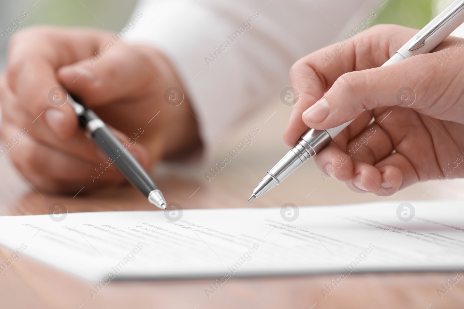 Photo of Businesspeople signing contract at table in office, closeup