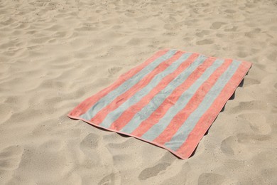 Photo of Soft striped beach towel on sunlit sand