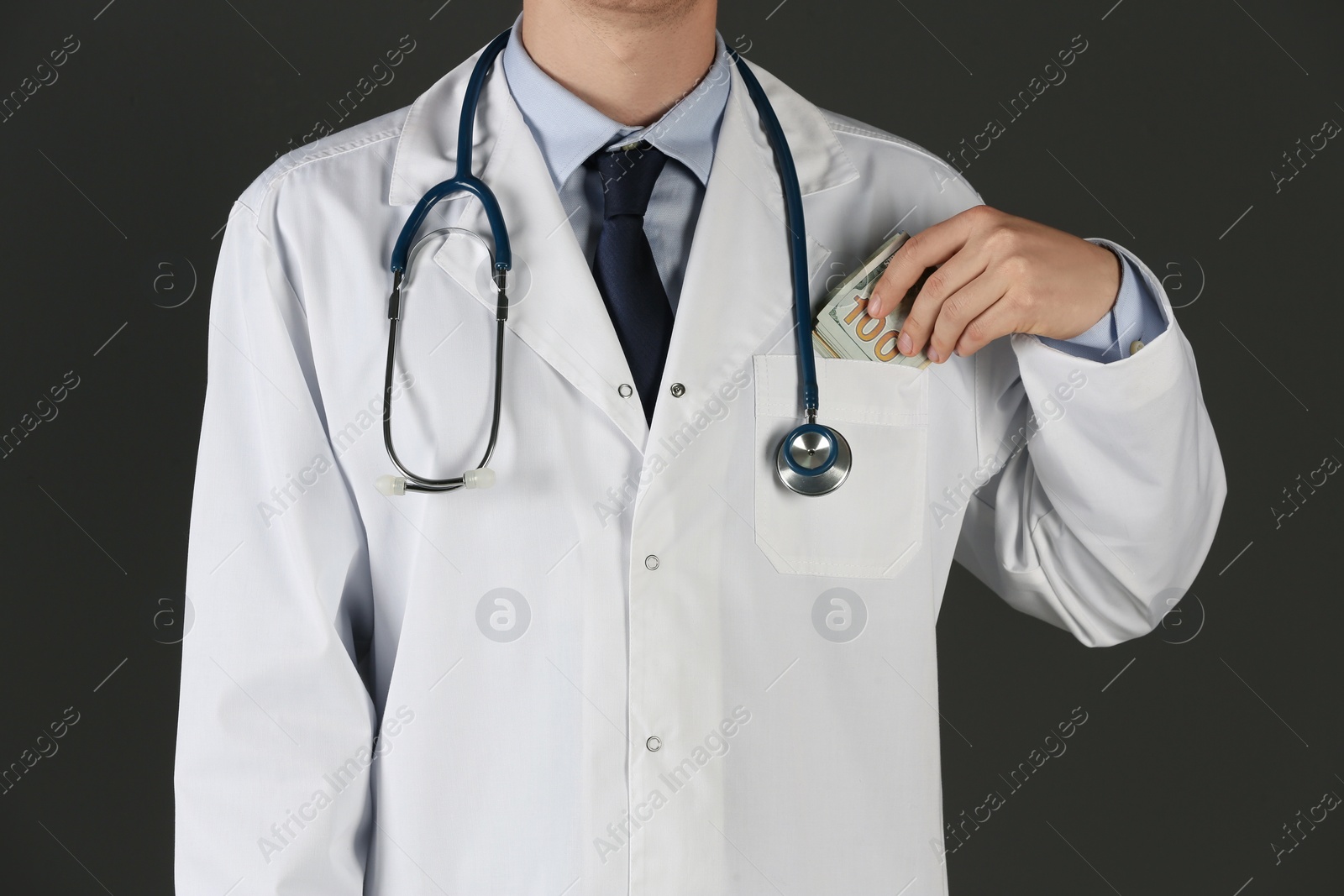 Photo of Doctor putting bribe into pocket on black background, closeup. Corruption in medicine