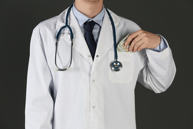 Photo of Doctor putting bribe into pocket on black background, closeup. Corruption in medicine