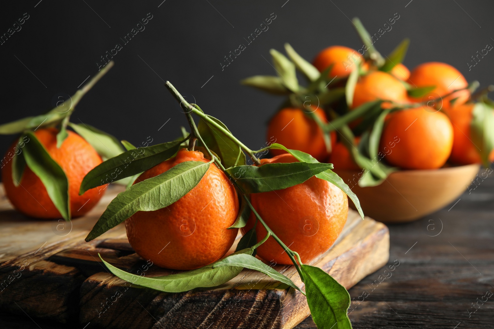 Photo of Wooden board with ripe tangerines on table