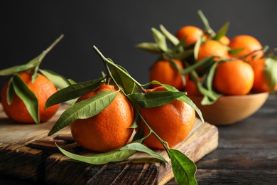 Photo of Wooden board with ripe tangerines on table