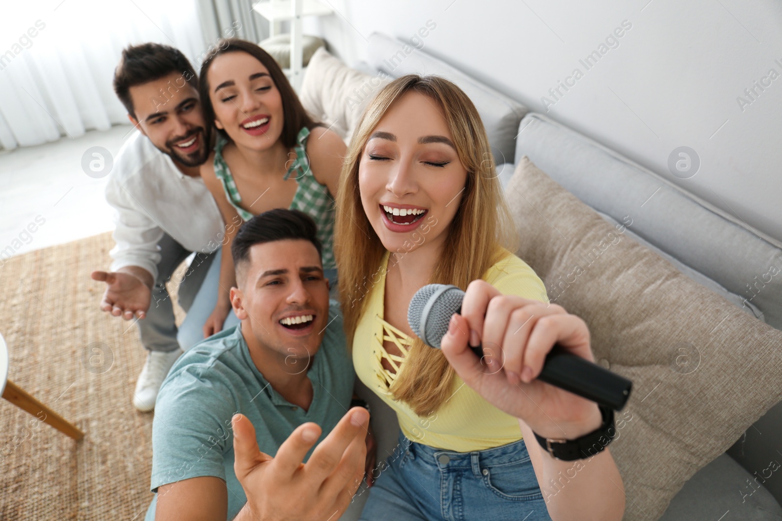 Photo of Happy friends singing karaoke together at home