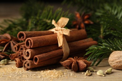 Photo of Different aromatic spices and fir branches on wooden table, closeup