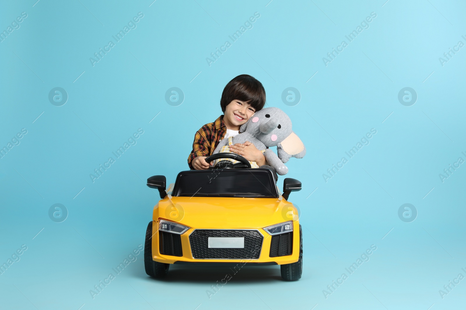 Photo of Little child with toy driving car on light blue background