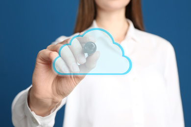 Image of Woman pointing at virtual cloud icon on blue background, closeup of hand. Data storage concept