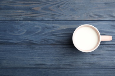 Photo of Cup of fresh milk on wooden table, top view. Space for text