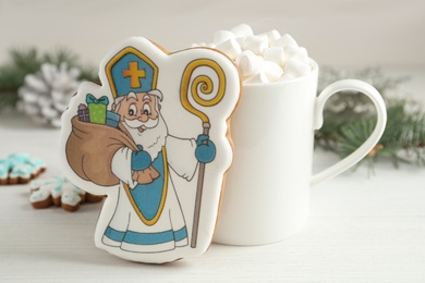 Photo of Delicious gingerbread cookies and hot drink on white wooden table. St. Nicholas Day celebration
