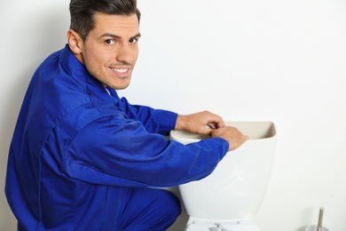 Photo of Professional plumber working with toilet bowl in bathroom