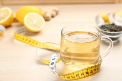 Photo of Diet herbal tea and measuring tape on wooden table, space for text