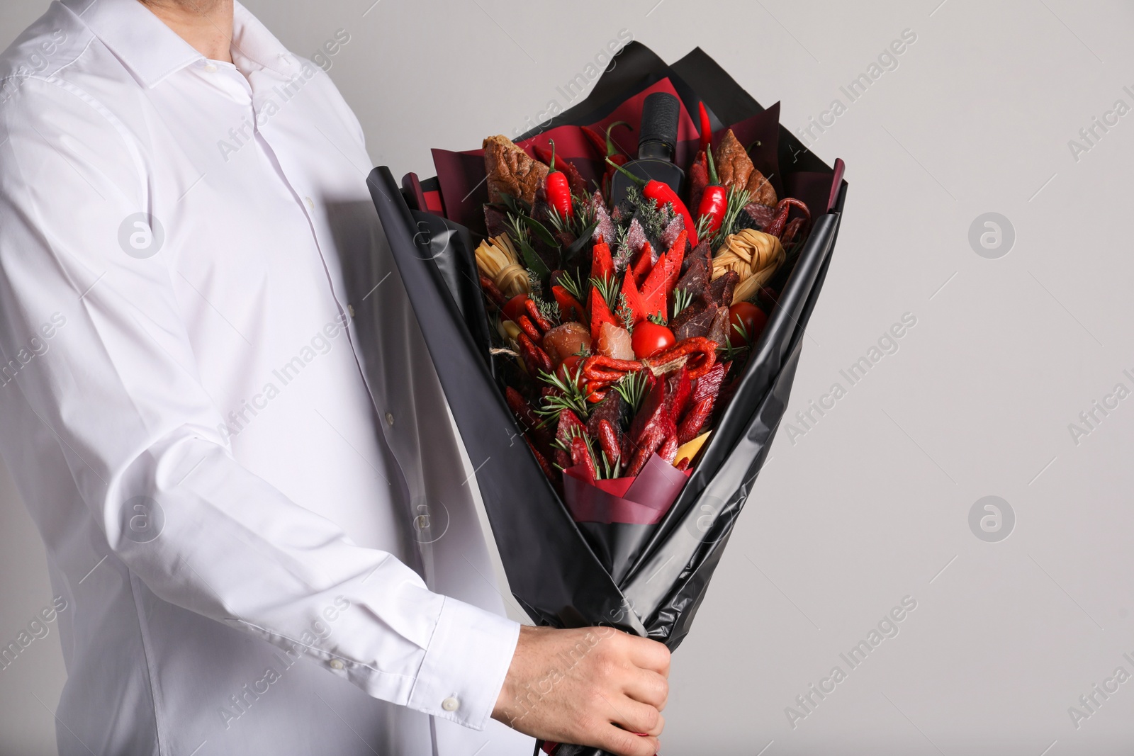 Photo of Man with beautiful food bouquet on light grey background, closeup