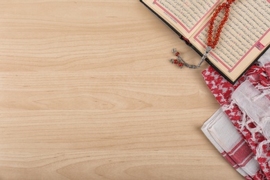 Flat lay composition with Muslim prayer beads, Quran and space for text on wooden background