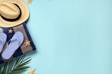 Photo of Beach towel, flip flops and hat on light blue background, flat lay. Space for text