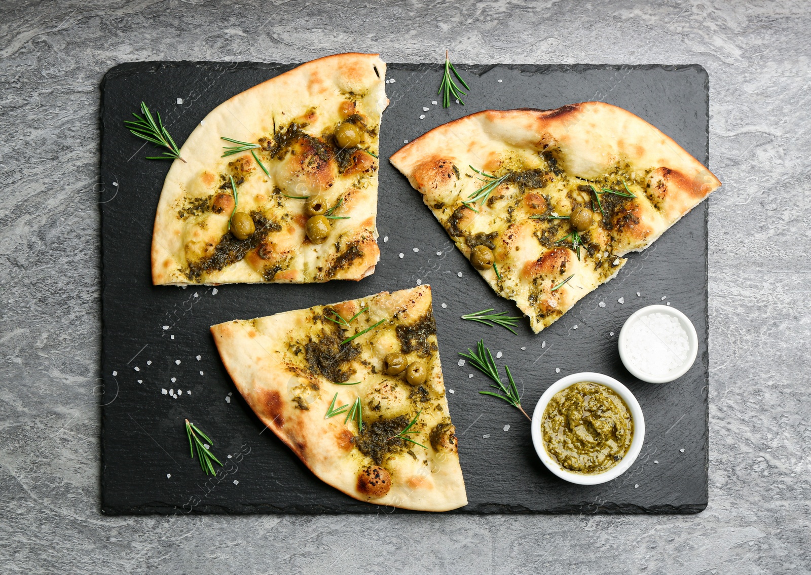 Photo of Delicious focaccia bread with green olives on grey table, flat lay