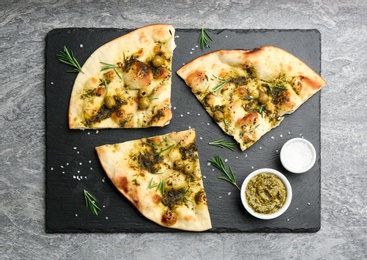 Photo of Delicious focaccia bread with green olives on grey table, flat lay