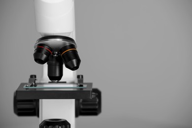 Photo of Modern microscope on grey background, closeup. Space for text