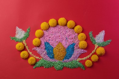 Happy Diwali. Composition with colorful rangoli and chrysanthemum flowers on red background, top view