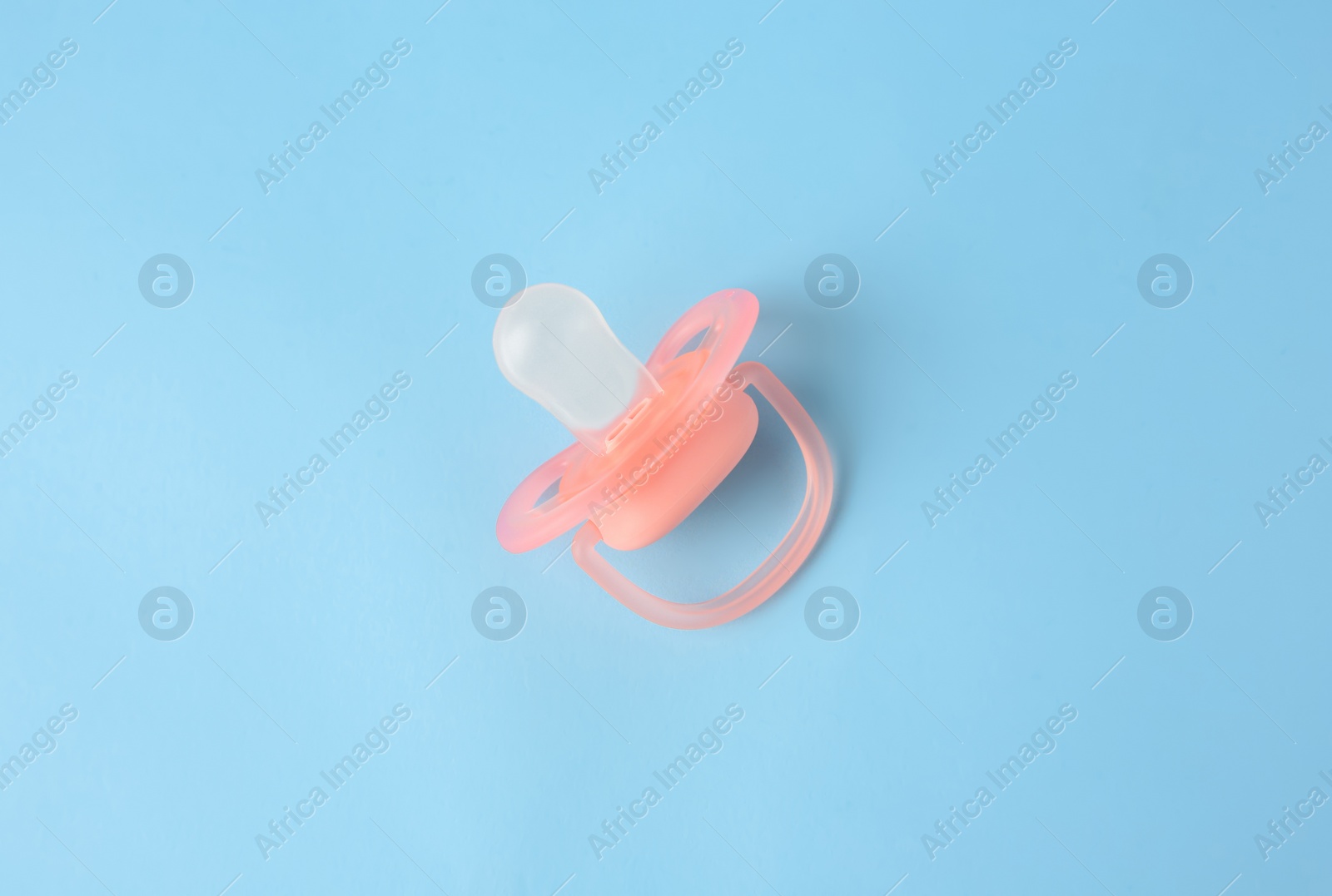 Photo of One new baby pacifier on light blue background, top view