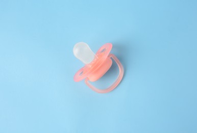 Photo of One new baby pacifier on light blue background, top view