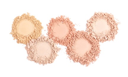 Samples of different crushed face powders on white background, top view