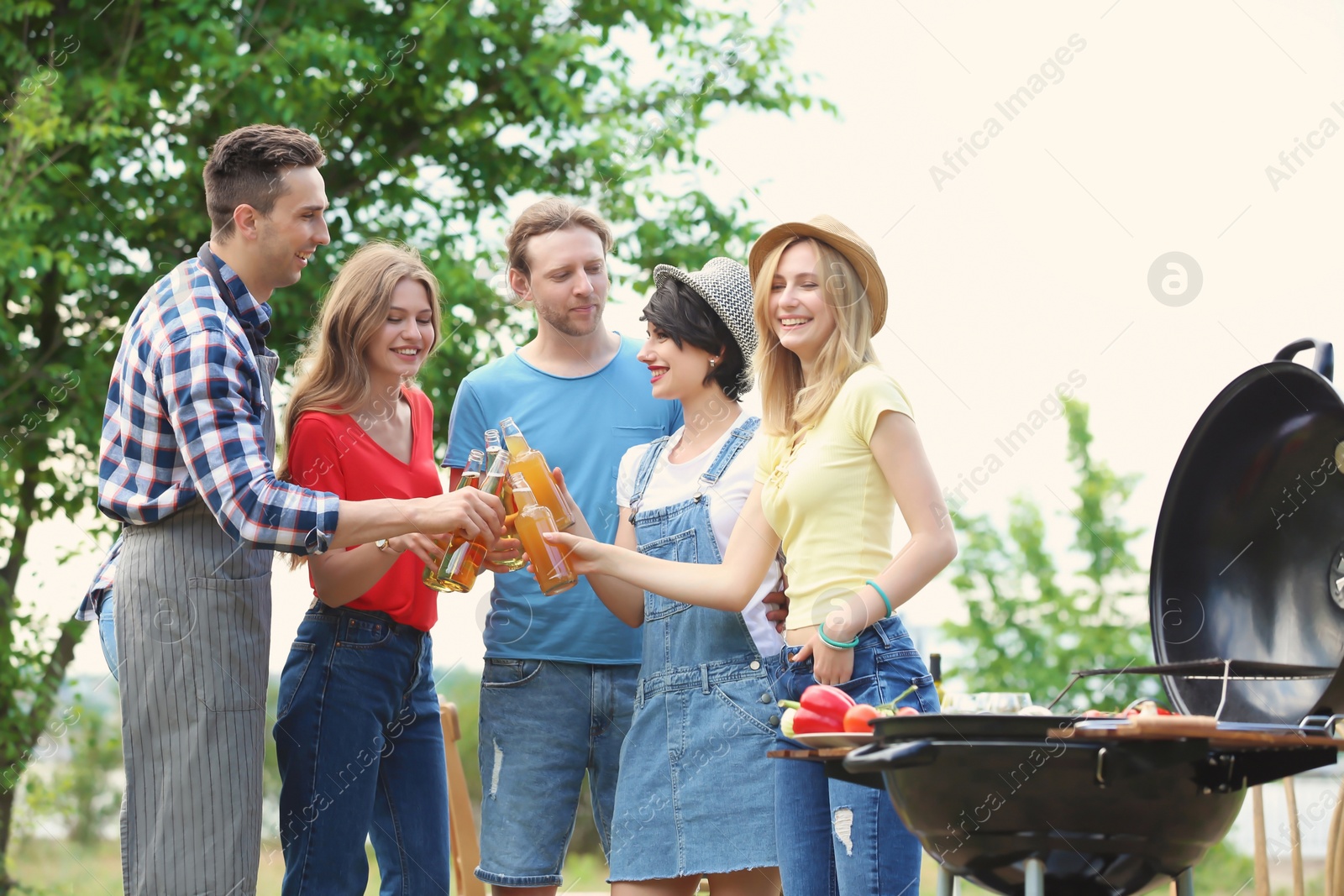 Photo of Young people having barbecue with modern grill outdoors