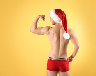 Shirtless young Santa Claus with sexy body on color background