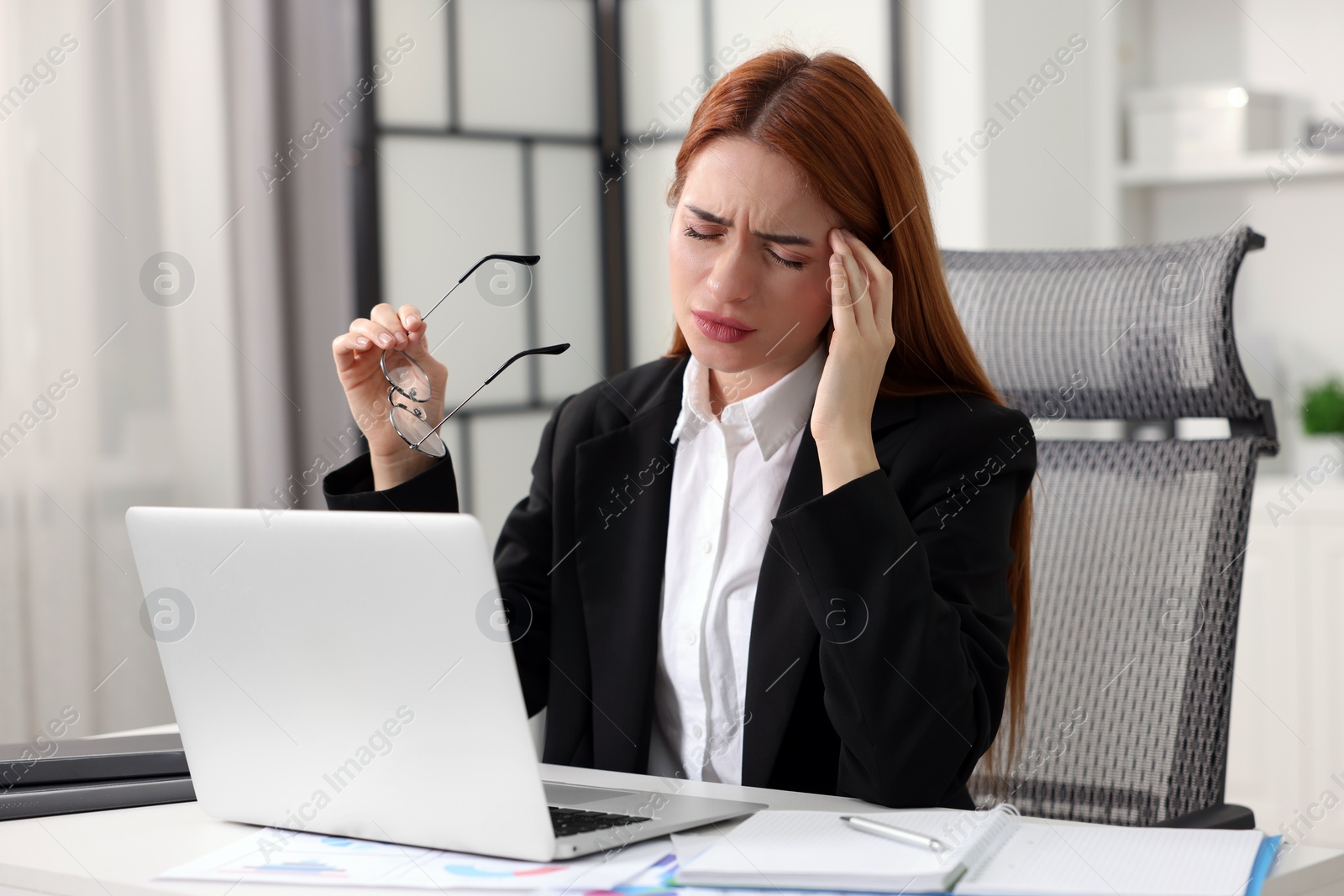 Photo of Woman suffering from headache at workplace in office