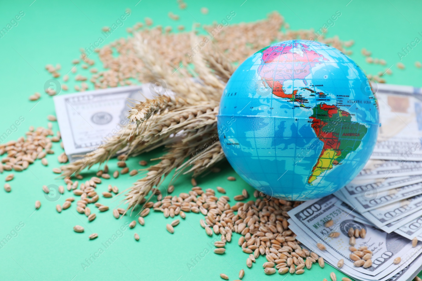 Photo of Import and export concept. Globe, wheat grains, and banknotes on green background, closeup
