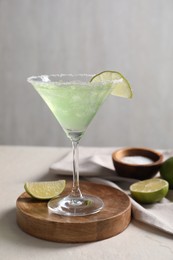 Photo of Delicious Margarita cocktail in glass, salt and lime on light table