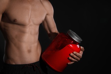 Photo of Athletic man with big red jar on black background, closeup. Doping concept