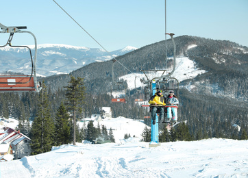 Photo of People using chairlift at mountain ski resort. Winter vacation