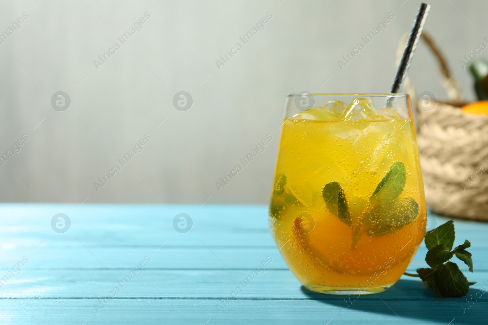 Photo of Delicious orange soda water on light blue wooden table. Space for text