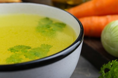 Photo of Delicious chicken bouillon with parsley on grey table, closeup
