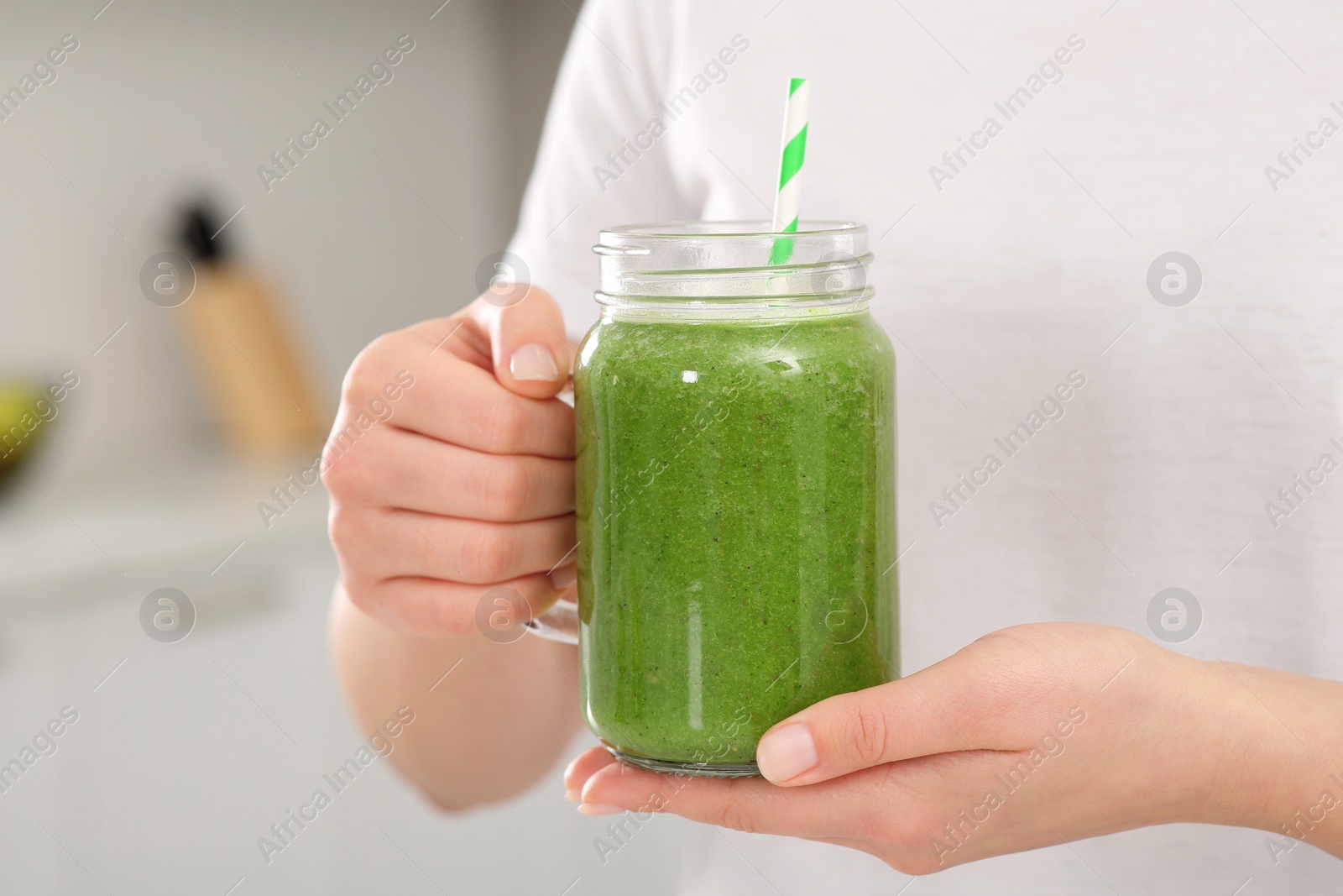 Photo of Woman holding delicious smoothie indoors, closeup view
