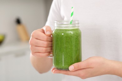 Photo of Woman holding delicious smoothie indoors, closeup view