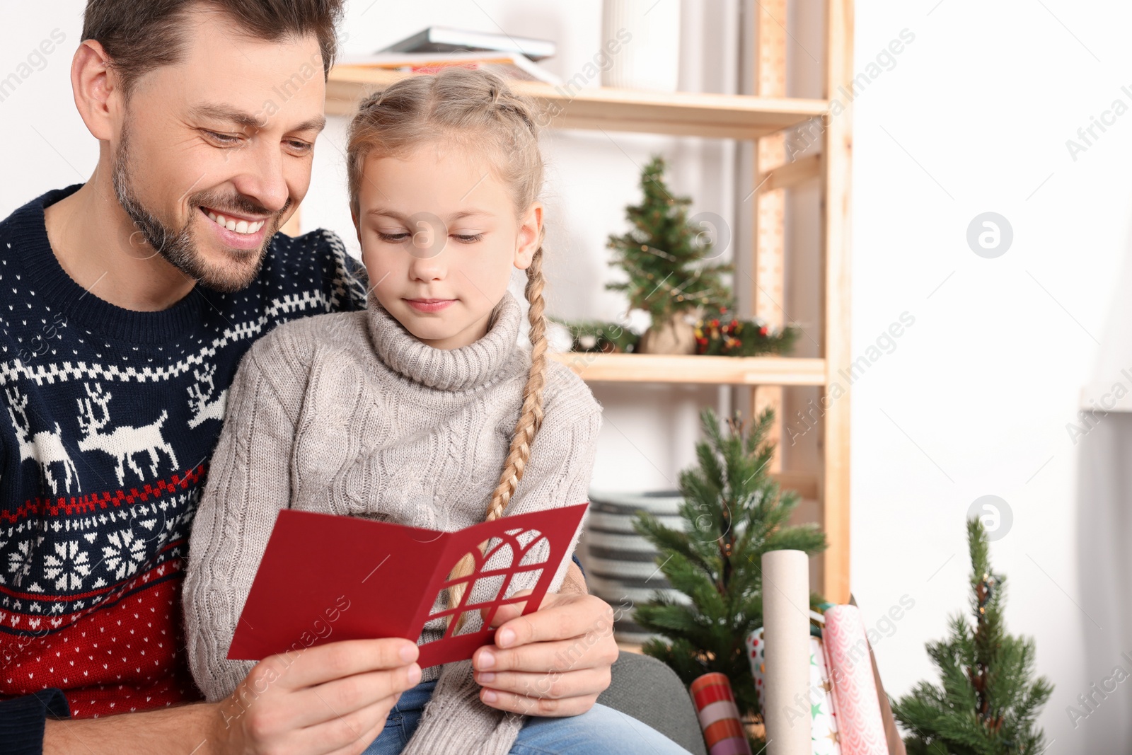 Photo of Happy man receiving greeting card from his daughter at home